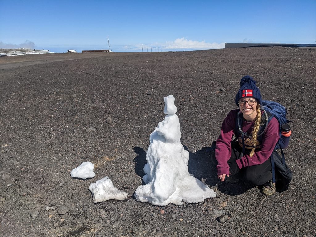 Sitting Next To A Snowman At The Top of Mauna Kea In Hawaii.
