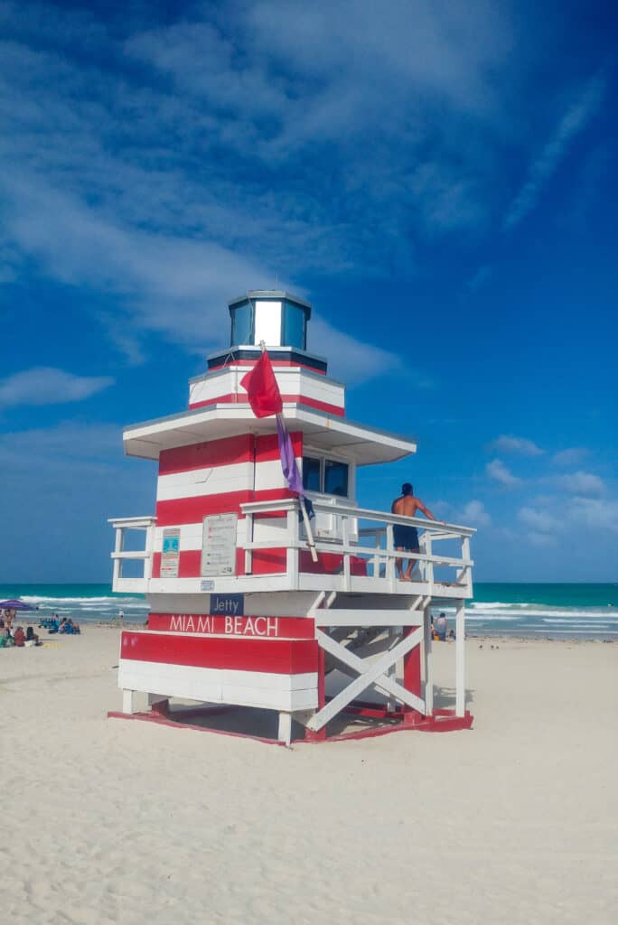 South Beach lifeguard tower on the sandy beach with a lifeguard watching the ocean.