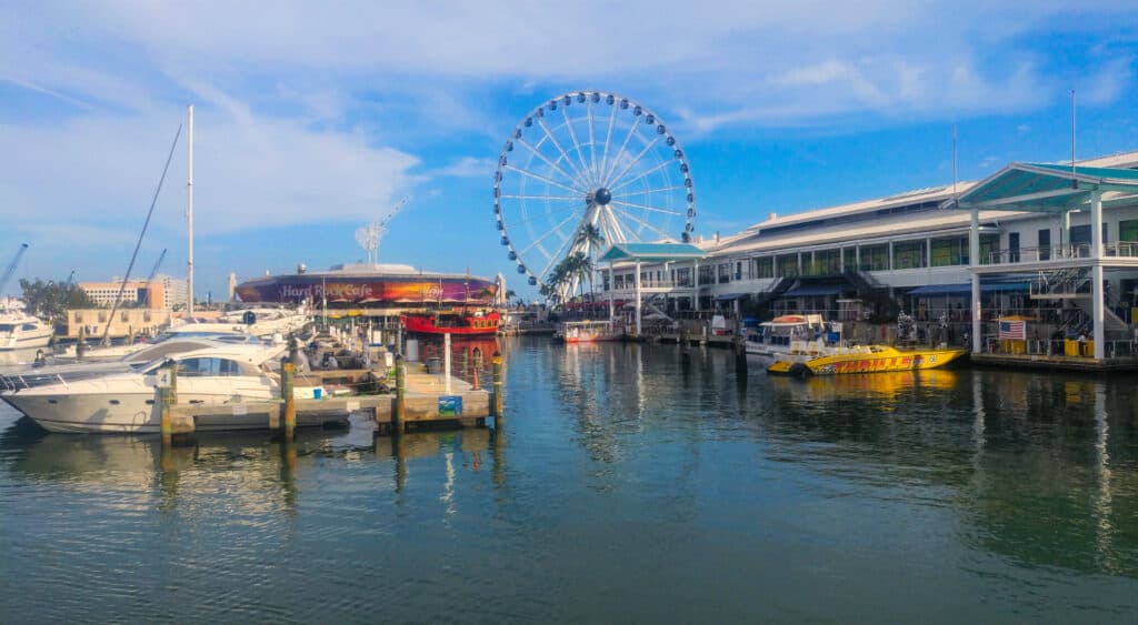 Bayside Marketplace in Miami with boats dotted around the docks, a shopping pavilion and observation wheel in the distance.