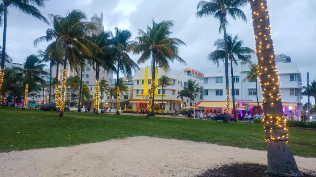 Ocean Drive in Miami at dusk with palm trees wrapped in lights.