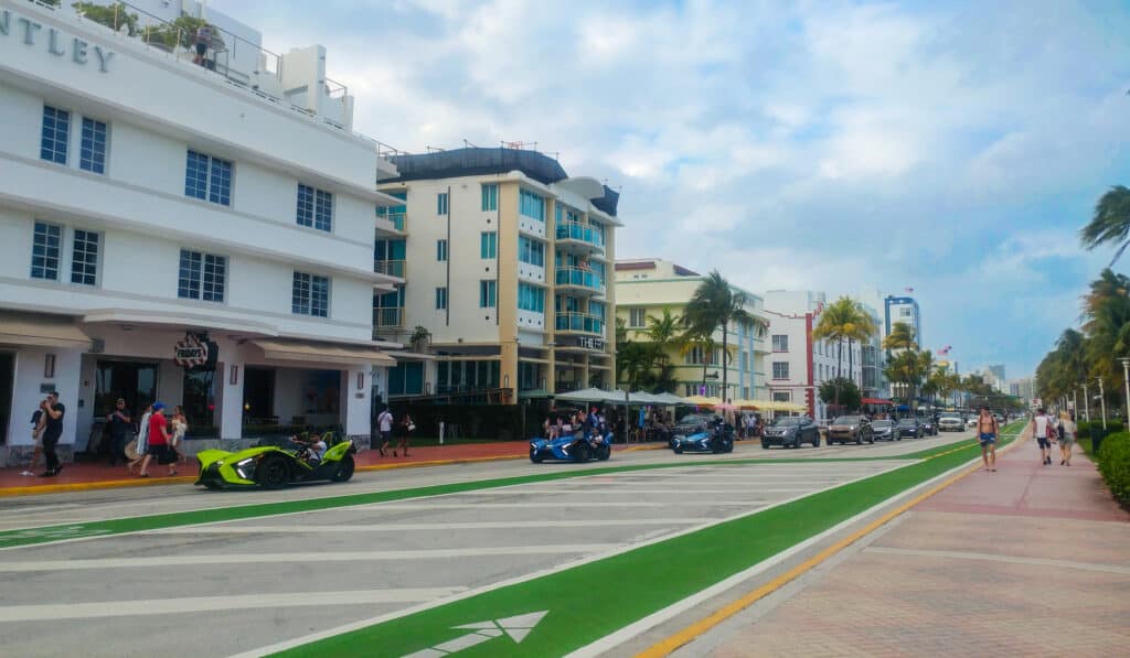Luxury cars and ATV rentals riding in convoy down the avenue in Miami.