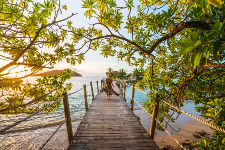 Woman walking down wood bridge to Overwater Bungalow in Fiji