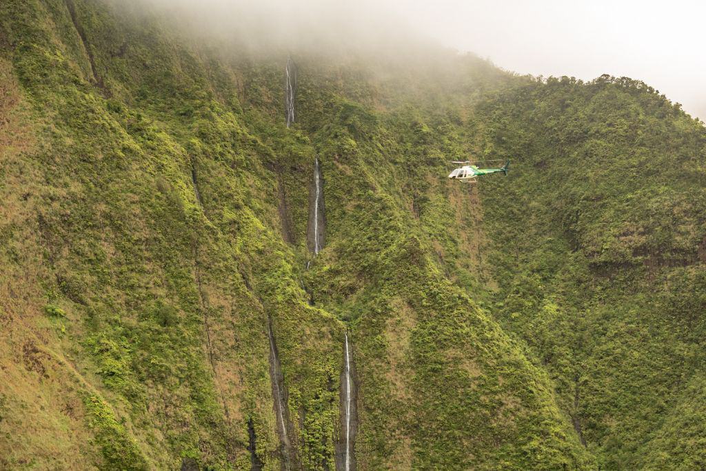 Helicopter flying alongside mountain