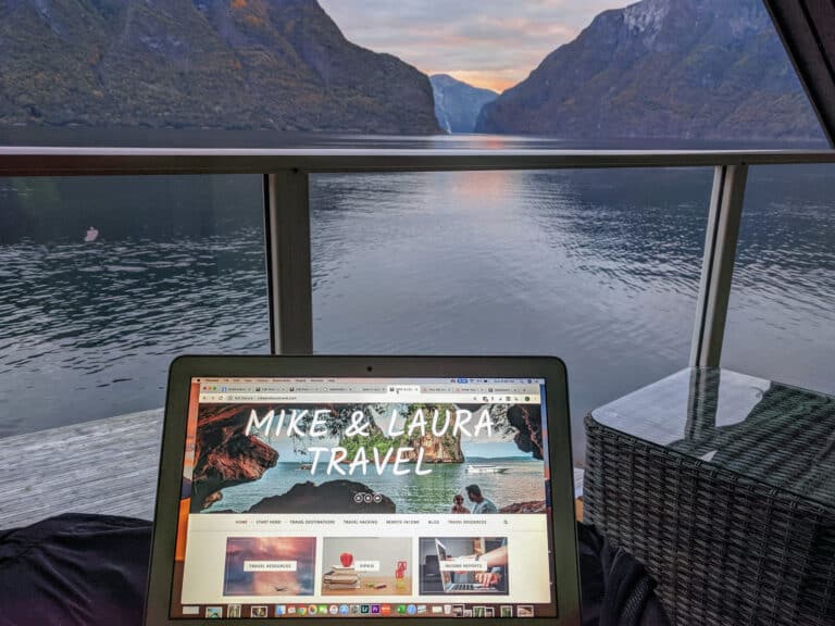 A photo of a computer with Mike & Laura Travel website with the fjords of Norway in the background.