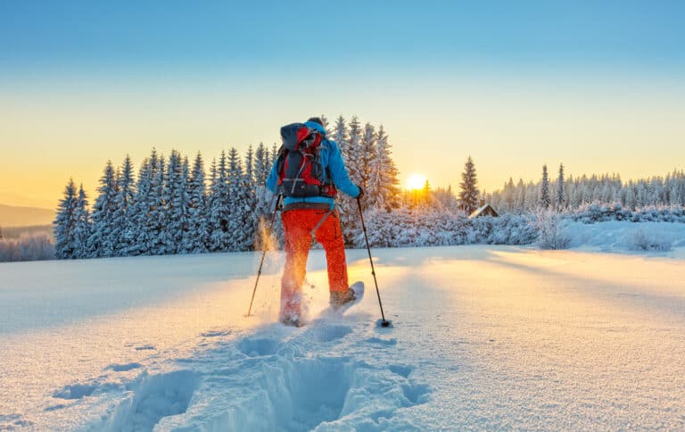 Snowshoe walker running in powder snow with beautiful sunrise light. Outdoor winter activity and healthy lifestyle