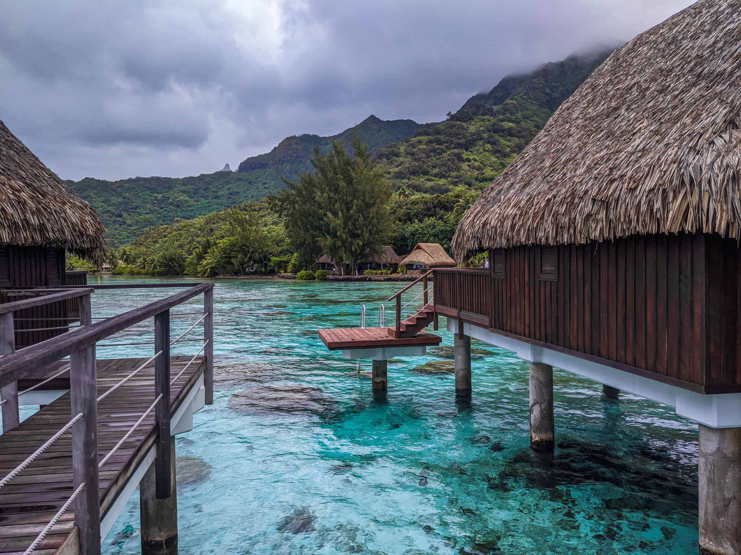 A view between the overwater bungalows at the Sofitel Kia Ora Moorea with the lush landscape in the background.