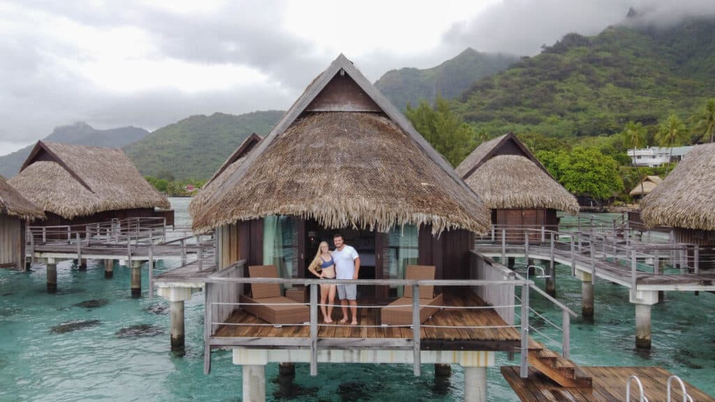 Mike and Laura standing on the deck of their overwater bungalow at Sofitel Kia Ora Moorea.