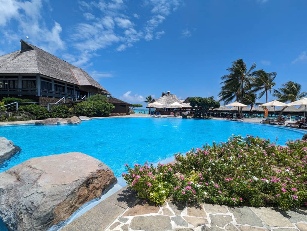 A view over the pool at the Hilton Moorea with sun loungers and flowers around it.