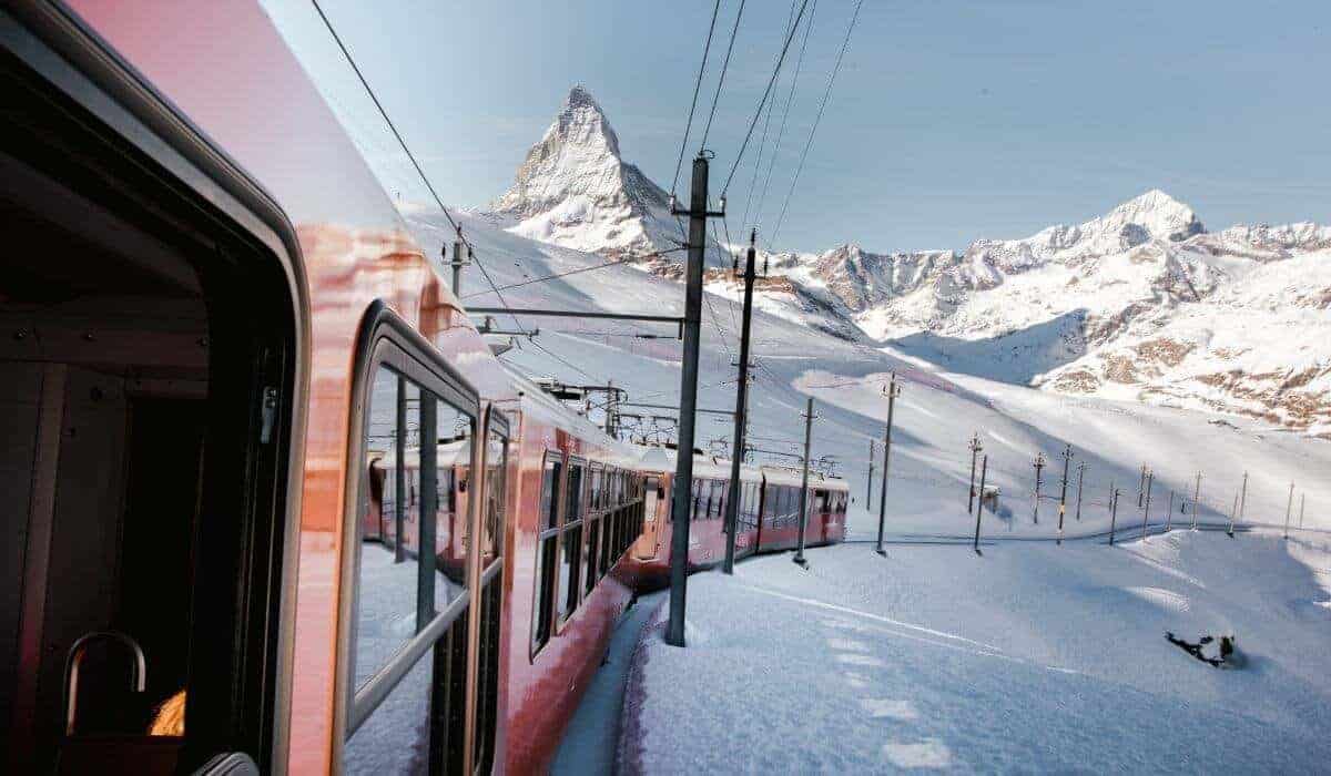 A view of the Gornergrat Cogwheel train winding through the snowy winter landscape of Zermatt.
