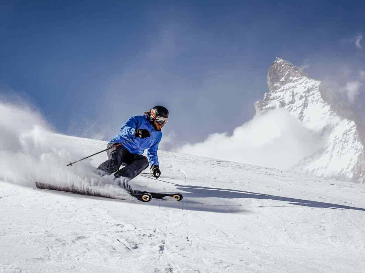 A skier in blue speeds down a snowy run in Zermatt.
