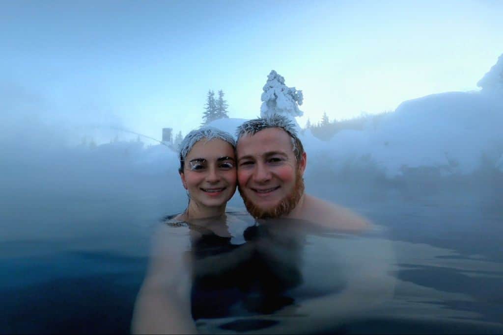Emily and Sean at a hot springs during winter with icicles on their eyes.
