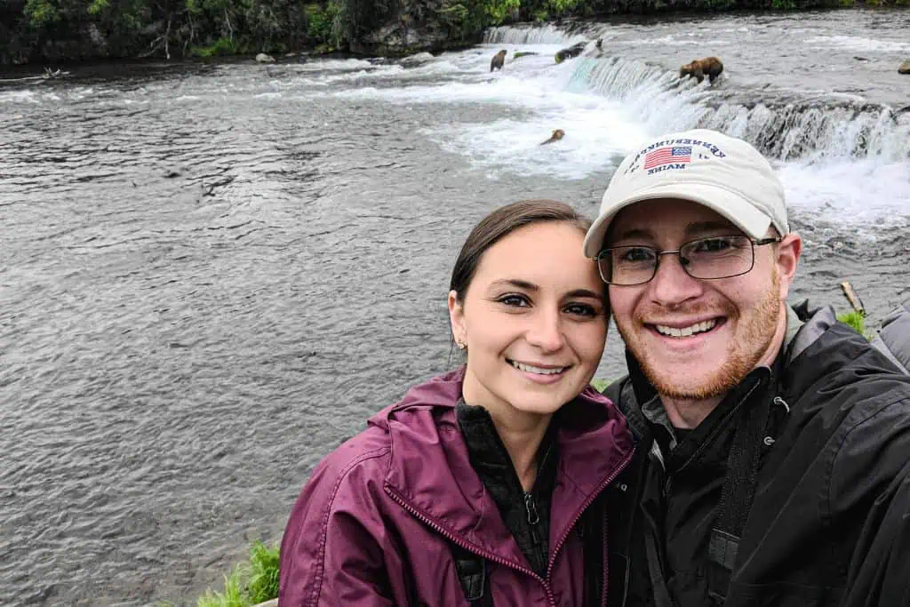 Emily and Sean in Katmai National Park in Alaska with grizzly bears behind them.