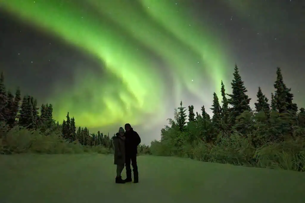 Emily and her husband, Sean, standing under the Northern Lights.