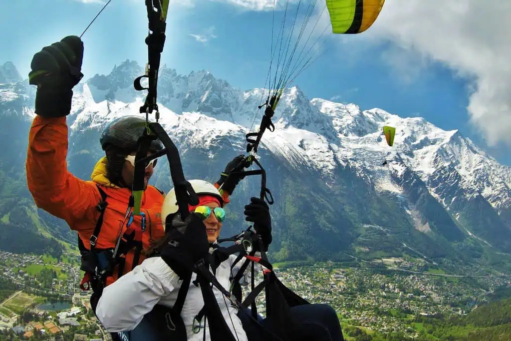 Emily parasailing in Europe with a guide and snow-covered mountains behind her.