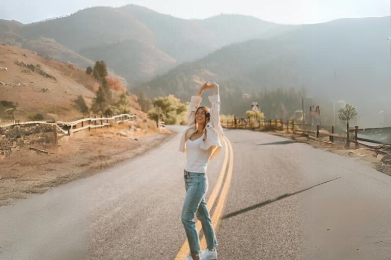 Dani from Dani The Explorer standing in the road in front of beautiful mountains in the background.