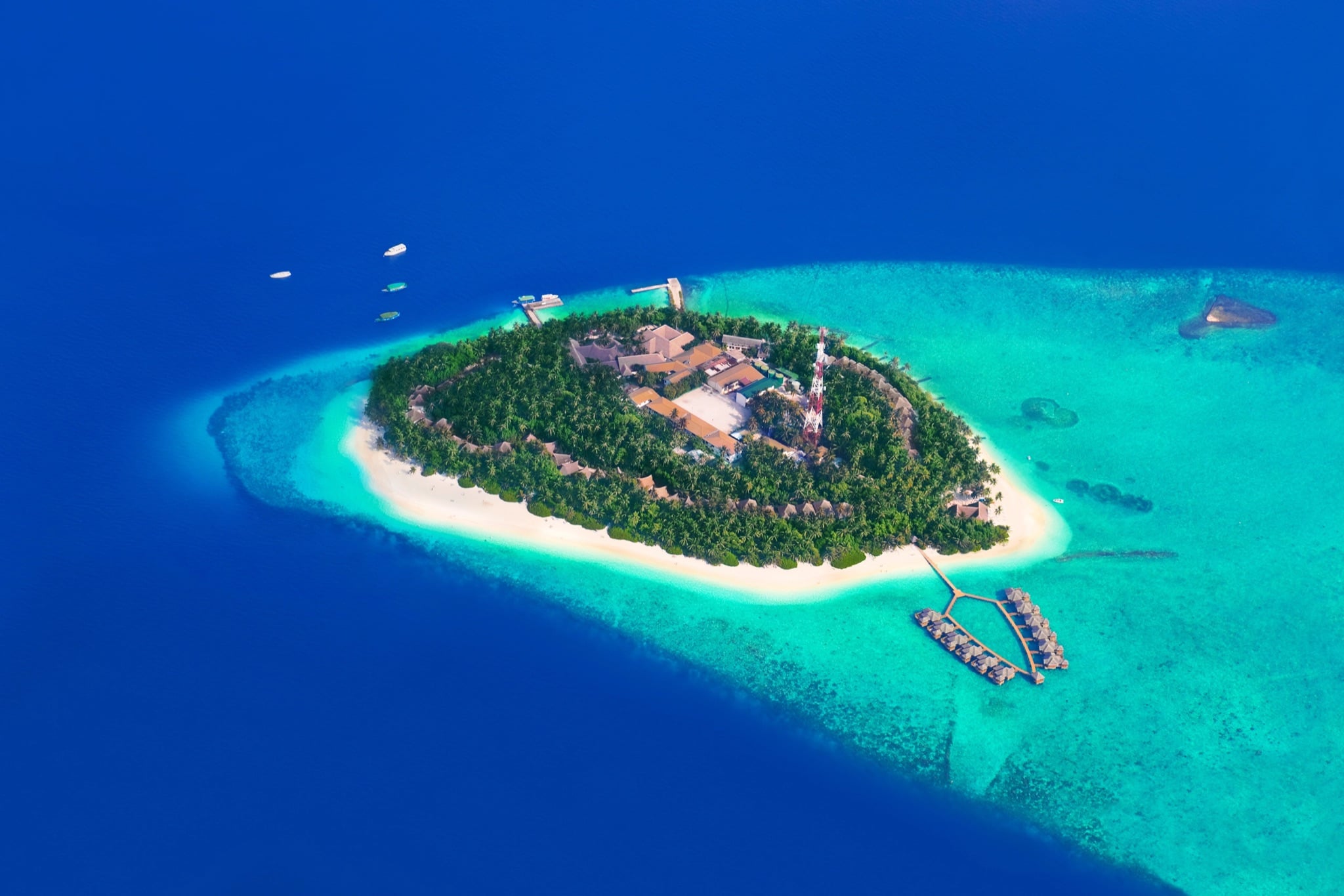 Small tropical island ringed by reef in the Maldives